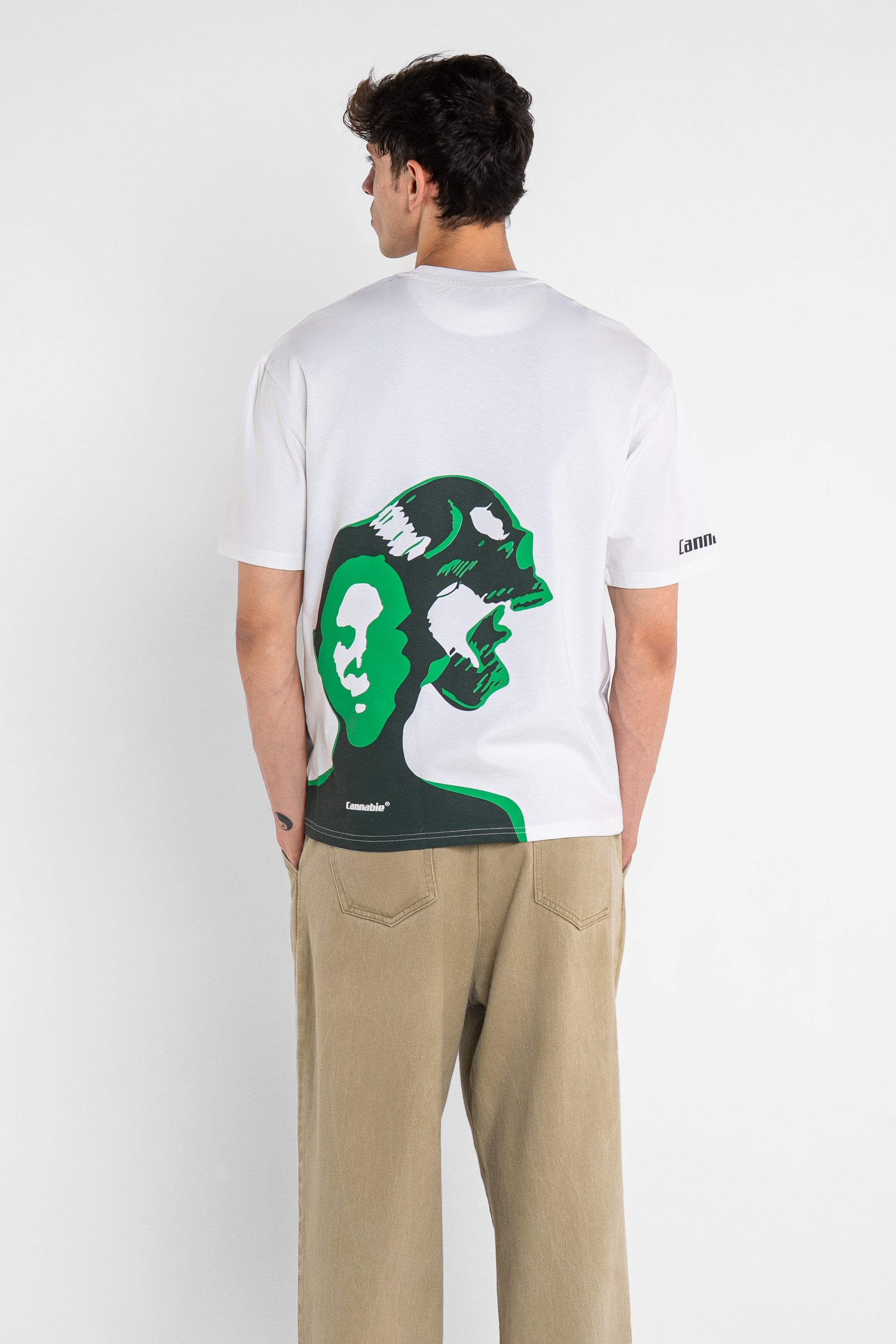 Person wearing a white t-shirt with a green graphic design on the back, standing against a plain background.